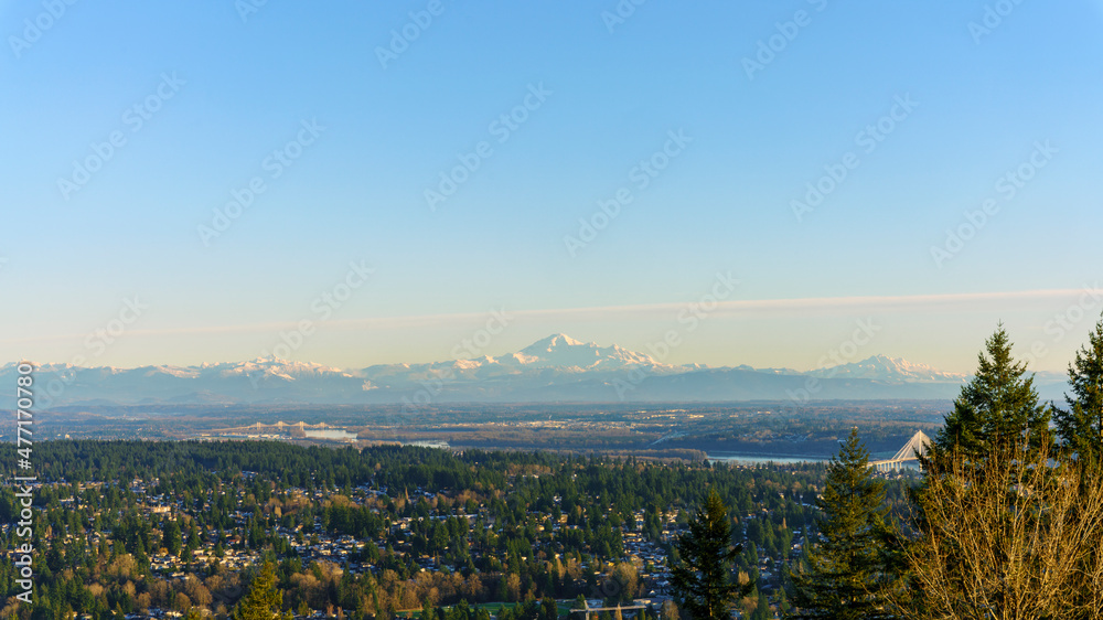 Panoramic winter view across Fraser Valley and river to alpine mountain range, including Mount Baker, on horizon.