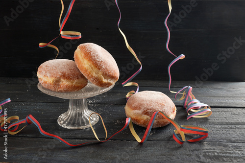 Fotografie, Obraz Berliner doughnuts or Krapfen with colorful party streamers on a dark rustic woo