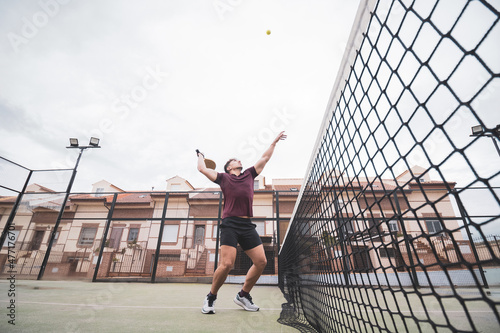 a young man jumping to hit a ball in a paddle tennis match. ©  Yistocking