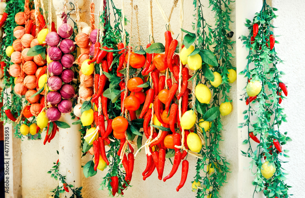 Fototapeta premium Bunches of onions, peppers, garlic hanging on the wall. Sold on the street, Italy
