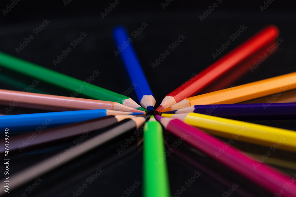 Fototapeta premium Group of colored pencils in a circle on a black background