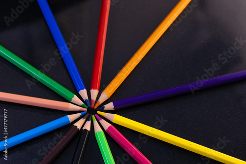 Group of colored pencils in a circle on a black background