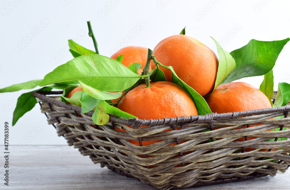 Tangerine in wicker basket, on table and light background.