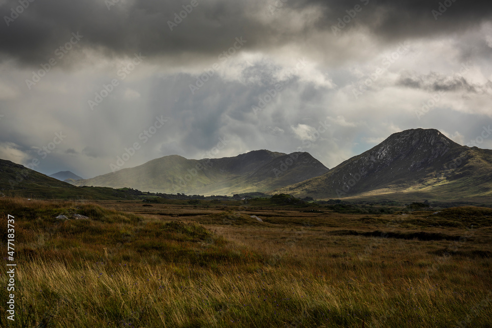 Sunbeams breaking through the clouds over the green sloping mountains of Connemara in County Galway in Ireland.