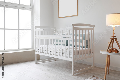 Comfortable crib near big window in children's room © Pixel-Shot