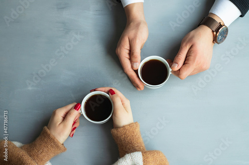 Fotografie, Obraz Cups of black tea or coffee in the hands of men and women on a gray background