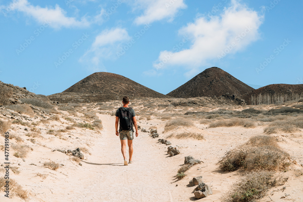 Traveling man on sandy mountain road