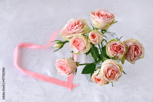 beautiful bouquet of white roses with delicate pink hue and  heart of satin pink ribbon on white silk background. Valentine's day. Selective focus