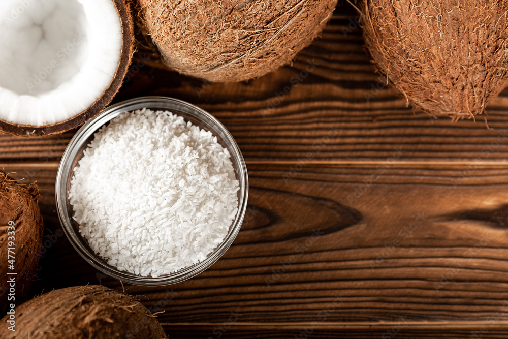 Coconut flakes in a bowl, coconuts on a wooden background. Close-up. copy space. Coconut flakes in a bowl, coconuts on a wooden background. Close-up. copy space.