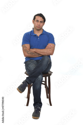 front view of man with ponytail and casual clothing legs and arms crossed sitting a chair on white background