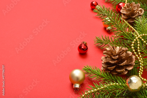 Christmas background with cones and a fir branch on a red background.