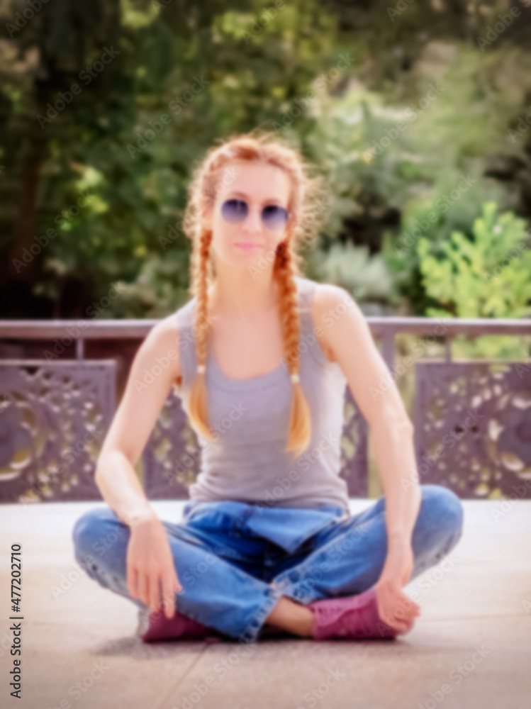 Girl with two pigtails sits cross-legged on the granite floor in the park. Blurred image Girl with two pigtails sits cross-legged on the granite floor in the park. Blurred image