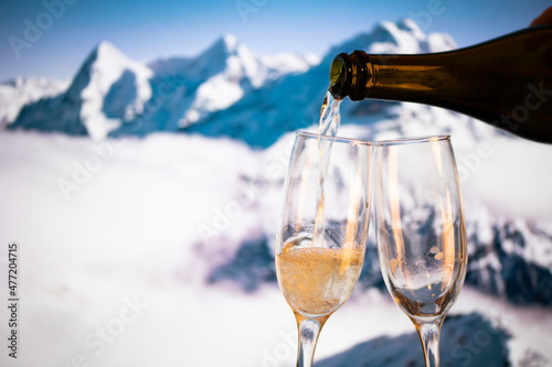 champagne glasses and snowy peaks in background New Year