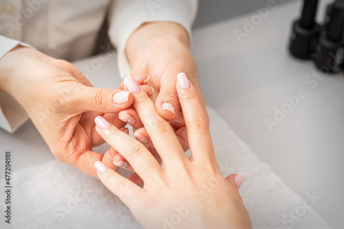Manicure treatment at beauty spa. A hand of a woman getting a finger massage with oil in a nail salon