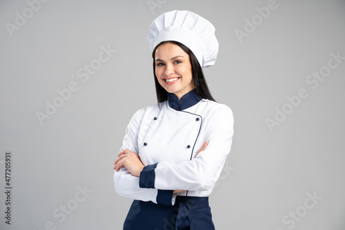 Chef woman wearing uniform and cap standing arms crossed and posing over isolated grey background. Occupation concept photo