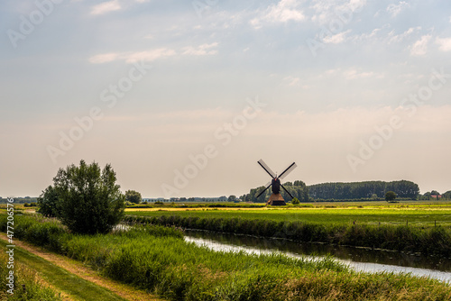 Polder landscape with the Uitwijkse Molen, a thatched hollow post mill, near the Dutch village of Sleeuwijk, province of North Brabant. The mill was built in the year 1700 and is a national monumenr