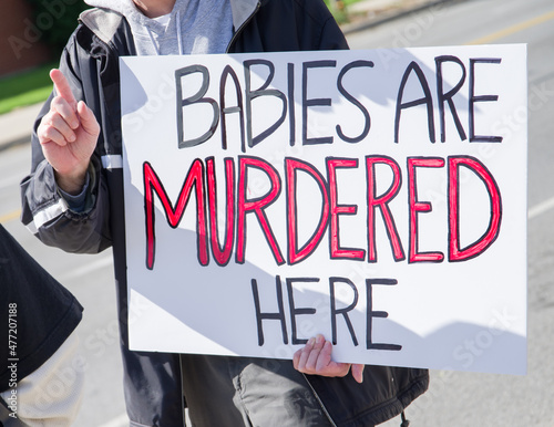 Obraz na płótnie person holding an abortion protest sign that says BABIES ARE MURDERED HERE