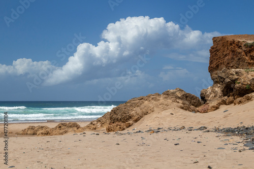 Fluffy white clouds reflecting the outline of the rocks on Cordoama Beach, Algarve, Portugal photo