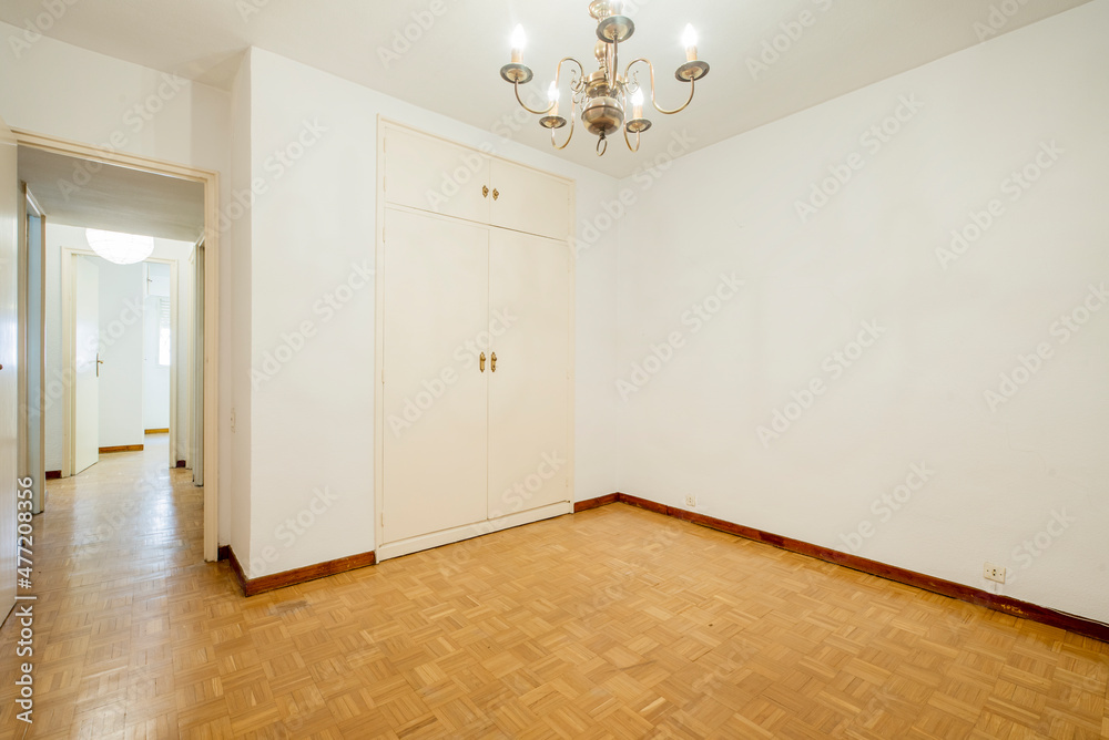 Empty room with built-in wardrobe with large lamp and parquet floors Empty room with built-in wardrobe with large lamp and parquet floors