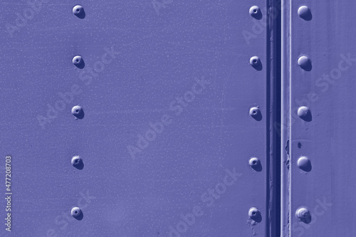 A metal surface with rivets, painted in trendy tone of Very Peri 17-3938. Color of the Year 2022.