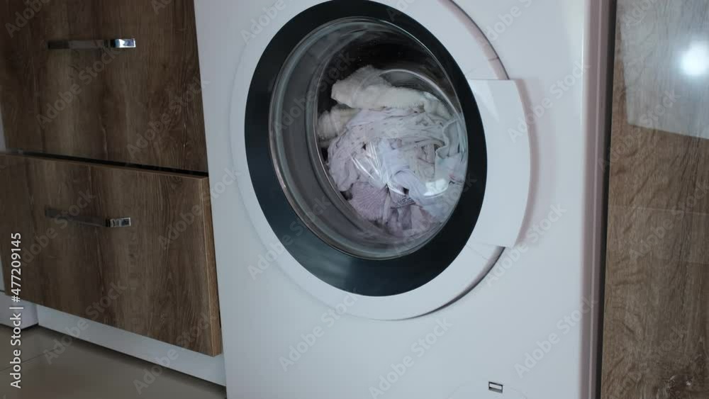 A woman's hand unloads washed wet laundry from the washing machine A woman's hand unloads washed wet laundry from the washing machine