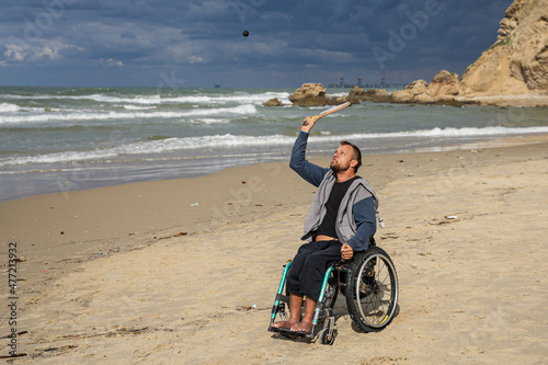 Wallpaper Mural Disabled man sitting on a wheelchair playing paddle ball on the beach Torontodigital.ca