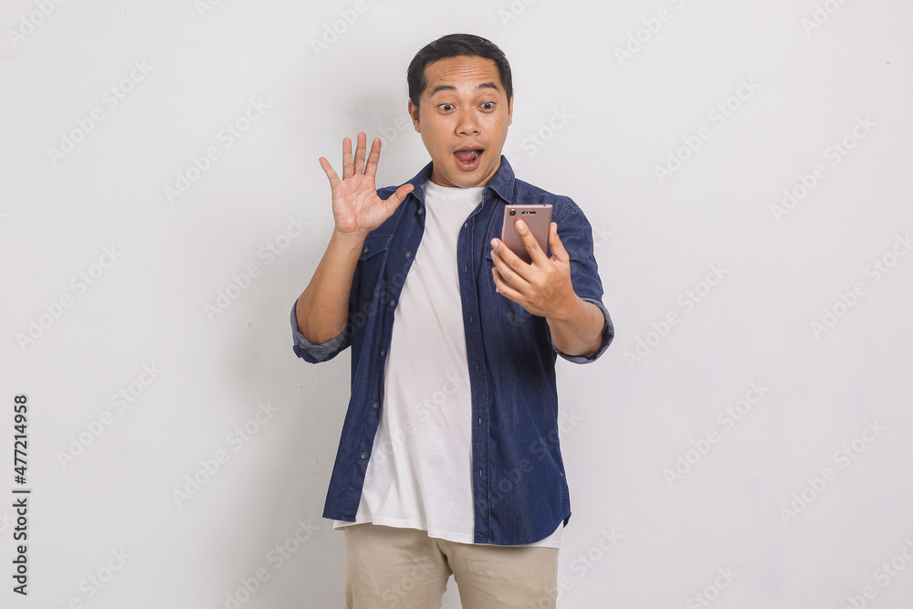 Portrait of handsome asian man being surprised looking at his mobile isolated on white background Portrait of handsome asian man being surprised looking at his mobile isolated on white background