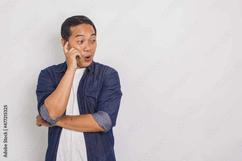 The astonished Asian youth stares sideways, opens mouth in surprise, copy space to insert text or slogan The astonished Asian youth stares sideways, opens mouth in surprise, copy space to insert text or slogan
