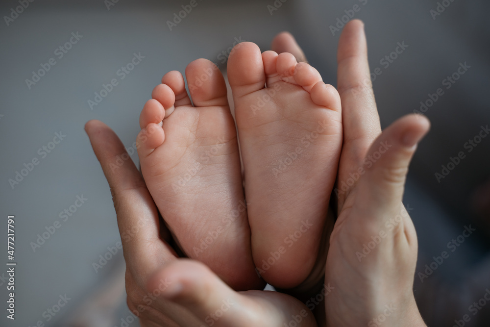 Mother holding little baby feet, selective focus. Newborn, love and care concept Mother holding little baby feet, selective focus. Newborn, love and care concept