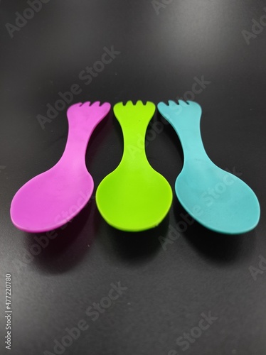Photo of multicolored fork and spoon 2 in 1 isolated on black background, Not Focus