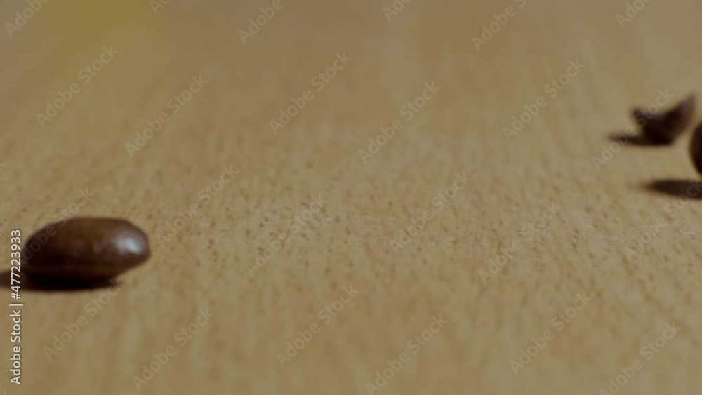 Coffee beans falling in slow motion onto a wooden table. Coffee beans falling in slow motion onto a wooden table.