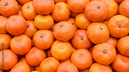 Fresh mandarins on fruit market, close up. Boxes full of ripe mandarin oranges for sale in supermarket. Fresh fruit display in shop. Juicy mandarin orange at the greengrocer's stall. 