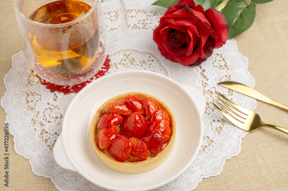 Fresh baked Strawberries Tart topping with strawberries sliced, served with hot tea on white lace placemat, good for sweet teatime Fresh baked Strawberries Tart topping with strawberries sliced, served with hot tea on white lace placemat, good for sweet teatime