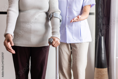 Nurse helping senior woman hand holding crutch trying to walk,Physical therapy concept