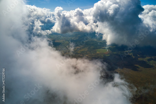 Aerial view from airplane window at high altitude of earth covered with puffy cumulus clouds forming before rainstorm © bilanol