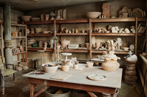 Photo Image of workplace of craftsperson with ceramic sculptures on the shelves