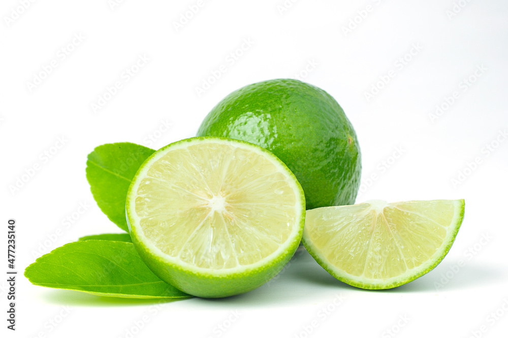 Whole Thai Green Lime halved and halved with green leaves on a white background. Whole Thai Green Lime halved and halved with green leaves on a white background.