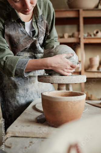 Close-up of worker making form of future vase from piece of clay working in ceramic workshop