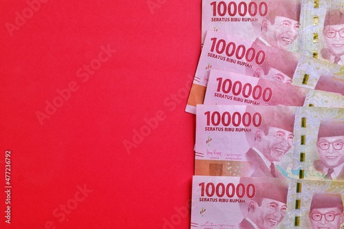 Rupiah the official currency of Indonesia. Business and finance concept. Uang 100000 Rupiah. Bank Indonesia. Red Background, Negative space, Copy space.
