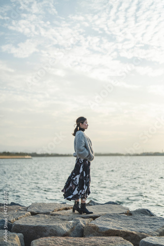 冬の夕暮れの海にいる女性