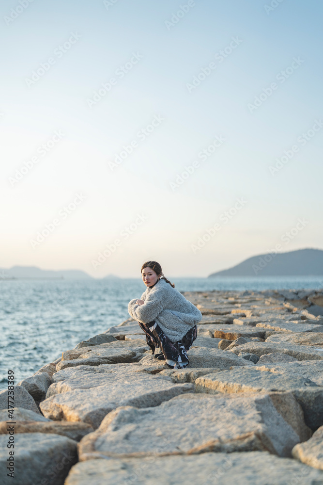 冬の夕暮れの海にいる女性