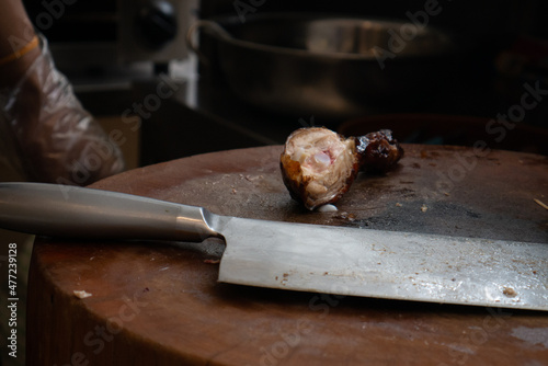 Close up of knife and grilled chicken on cutting board. Roasted chicken on cutting board. Chinese cuisine food.