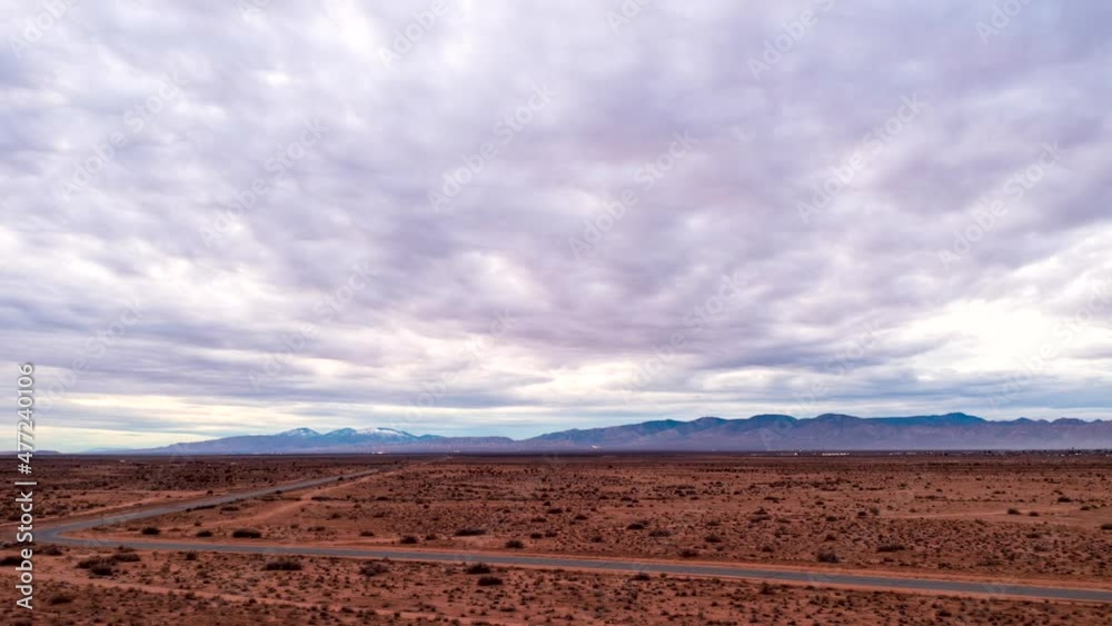 Mojave Desert and highway to California City with the mountains in the background and a cloudscape overhead - aerial hyper lapse