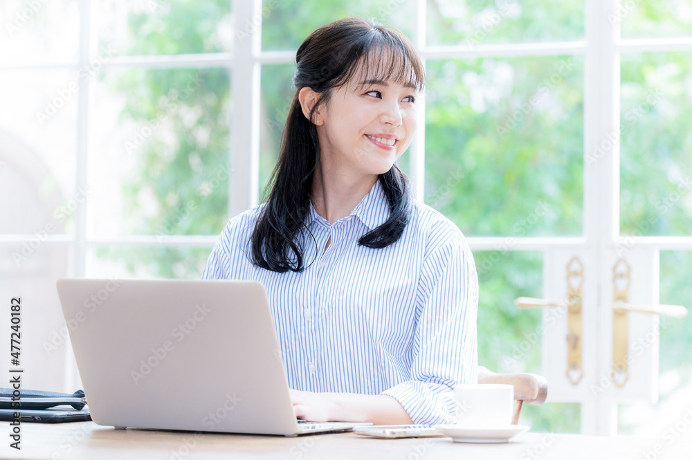 パソコンをしながら遠くを見つめる女性 パソコンをしながら遠くを見つめる女性