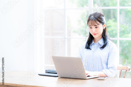 Beautiful Asian woman working on a computer with her head down, copy space available.