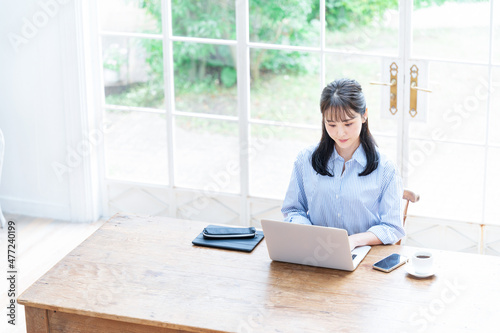 俯いてパソコンの仕事をする美しい日本人女性 コピースペースあり 広角 俯瞰