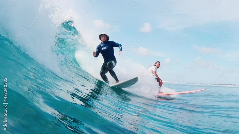 Two surfers ride the single ocean wave in Maldives