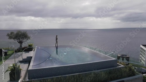 A female model at the rooftop of a hotel with an attached infinity pool looking out at the ocean. photo