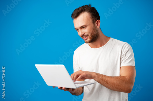 Handsome young man using his laptop against blue background