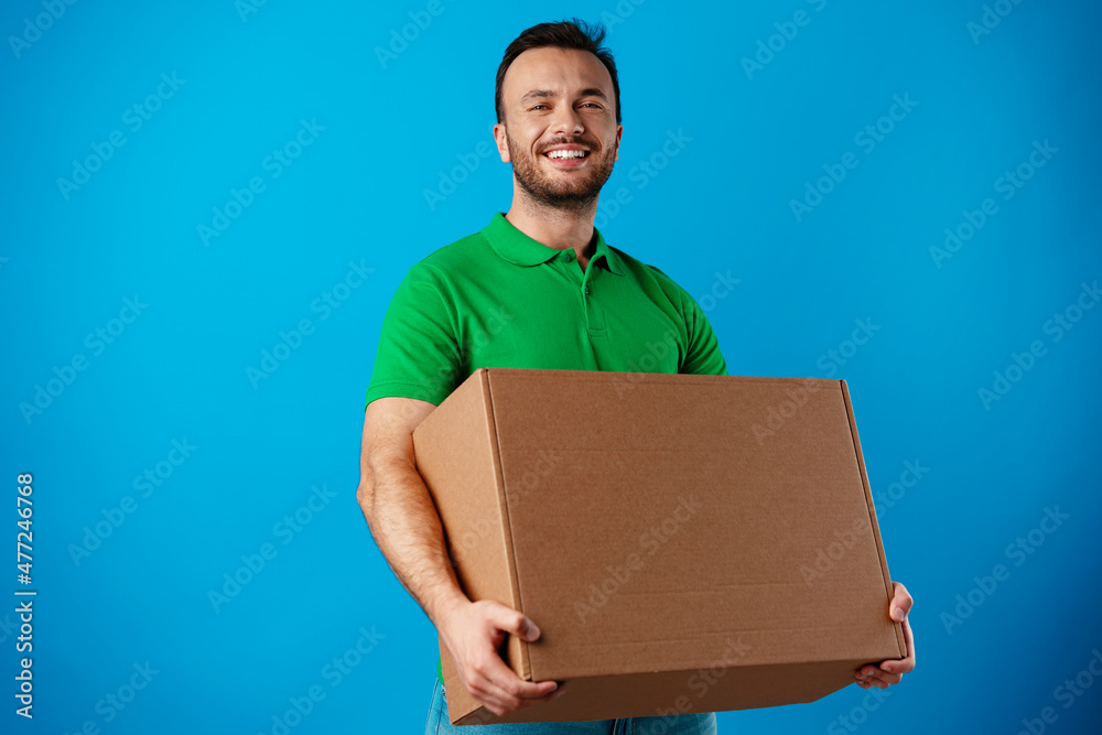 Delivery man with box in studio against blue background Delivery man with box in studio against blue background
